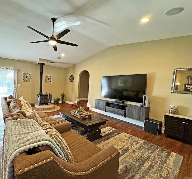 living room with lofted ceiling, dark wood-type flooring, a wood stove, and ceiling fan