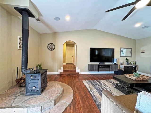 living room with vaulted ceiling, a wood stove, dark hardwood / wood-style flooring, and ceiling fan