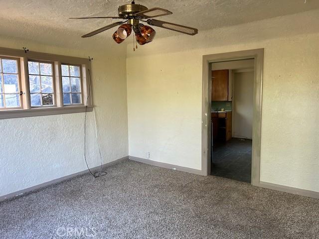 carpeted spare room featuring ceiling fan and a textured ceiling