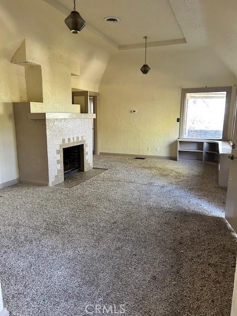 unfurnished living room with vaulted ceiling and a tiled fireplace