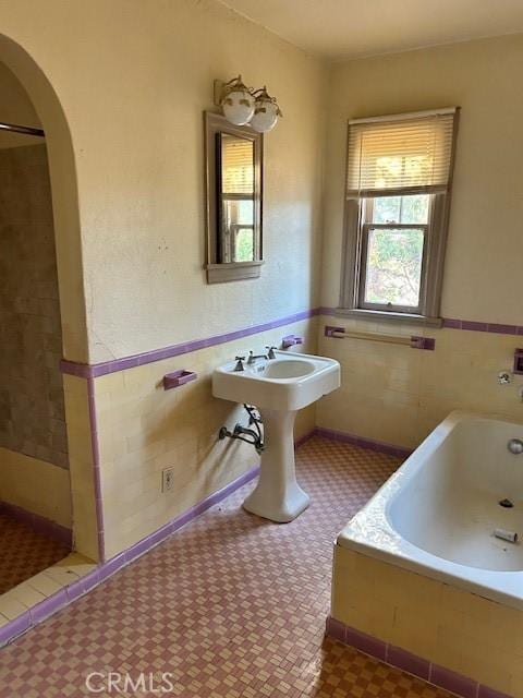 bathroom with plus walk in shower, tile walls, and sink