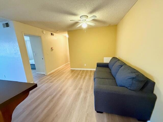 living room featuring a textured ceiling, ceiling fan, and light hardwood / wood-style floors