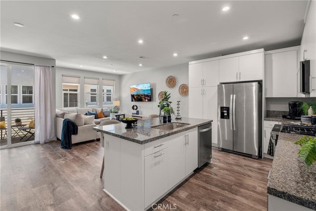 kitchen with white cabinets, appliances with stainless steel finishes, an island with sink, and sink