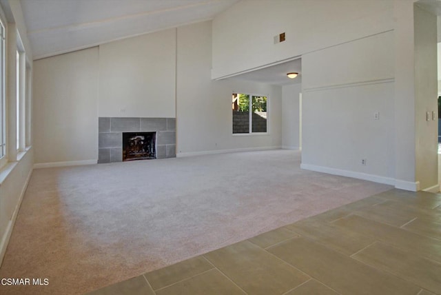 unfurnished living room featuring a fireplace, carpet floors, and high vaulted ceiling