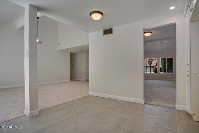 spare room featuring light colored carpet and vaulted ceiling