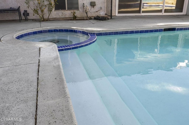 view of swimming pool featuring an in ground hot tub