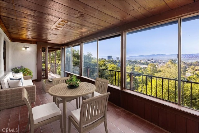 sunroom featuring a mountain view and wooden ceiling