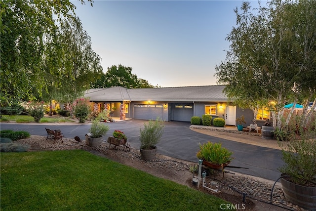 single story home with a garage and a lawn