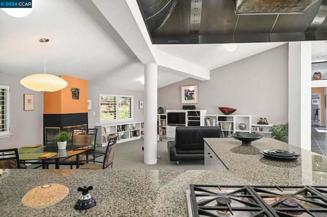 kitchen featuring lofted ceiling, light stone countertops, and stainless steel gas stovetop