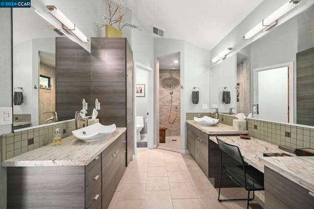 bathroom featuring lofted ceiling, tile patterned floors, vanity, backsplash, and toilet