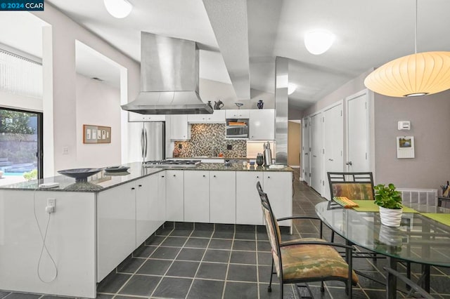 kitchen with white cabinetry, stainless steel appliances, decorative backsplash, pendant lighting, and wall chimney exhaust hood