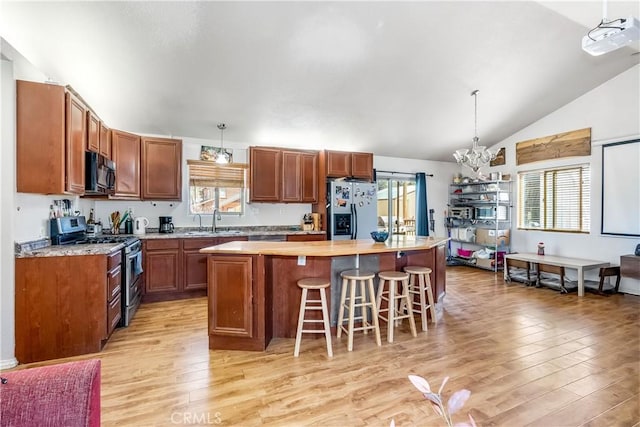 kitchen featuring stainless steel appliances, sink, decorative light fixtures, a chandelier, and a center island