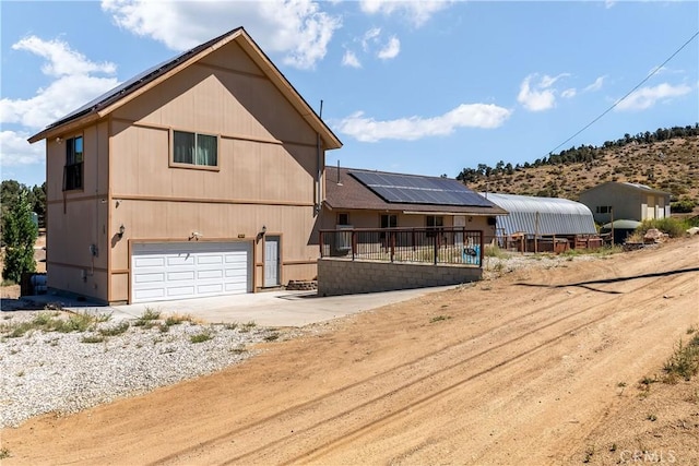 back of house featuring solar panels and a garage