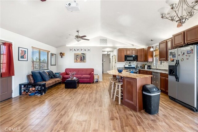 kitchen with a center island, a kitchen breakfast bar, decorative light fixtures, appliances with stainless steel finishes, and light wood-type flooring