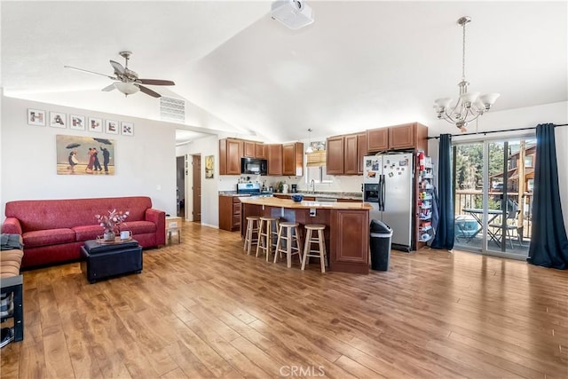 kitchen with a kitchen breakfast bar, vaulted ceiling, decorative light fixtures, a kitchen island, and stainless steel fridge with ice dispenser