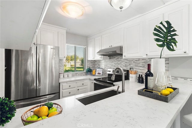 kitchen featuring light stone counters, white cabinets, kitchen peninsula, tasteful backsplash, and appliances with stainless steel finishes