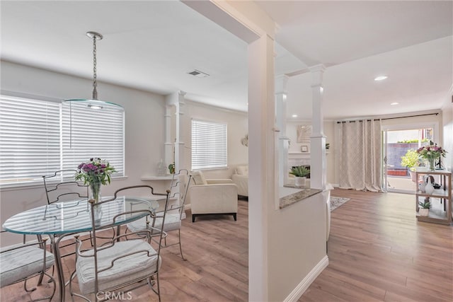 dining room with crown molding, decorative columns, and hardwood / wood-style flooring