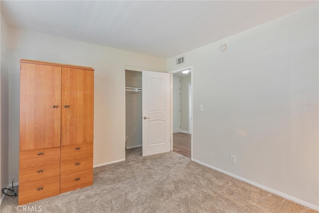 unfurnished bedroom featuring light carpet and a closet