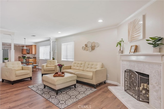 living room featuring light wood-type flooring, crown molding, and a high end fireplace