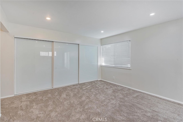 unfurnished bedroom with light carpet and a closet