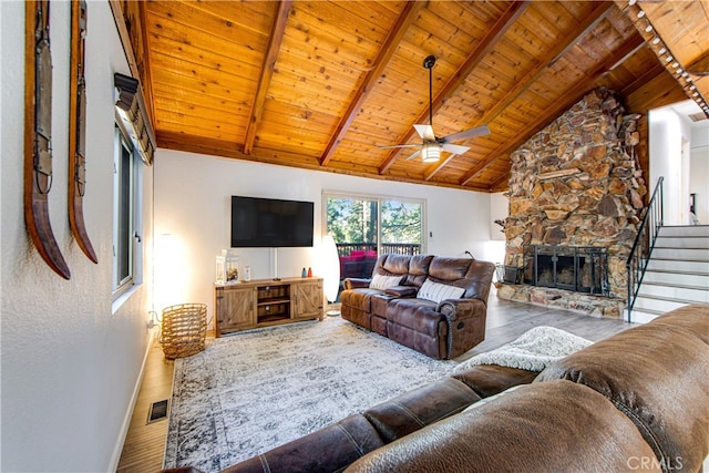 living room with wood ceiling, wood-type flooring, beamed ceiling, and a stone fireplace