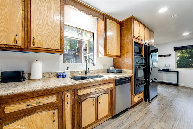 kitchen featuring sink, light wood-type flooring, black appliances, and light stone countertops