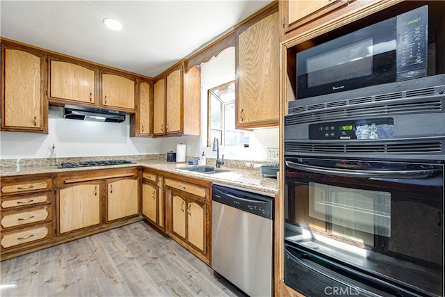 kitchen with light stone counters, light wood-type flooring, black appliances, and sink