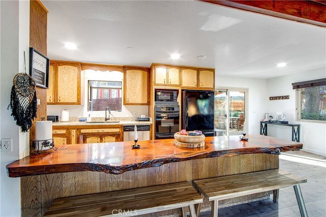 kitchen with sink, hardwood / wood-style floors, black appliances, and kitchen peninsula