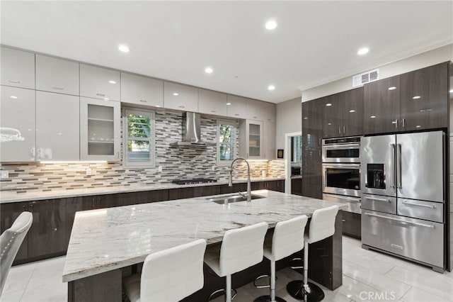 kitchen featuring appliances with stainless steel finishes, decorative backsplash, white cabinets, a kitchen bar, and a kitchen island with sink