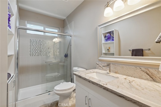 bathroom with vanity, toilet, and a shower with door