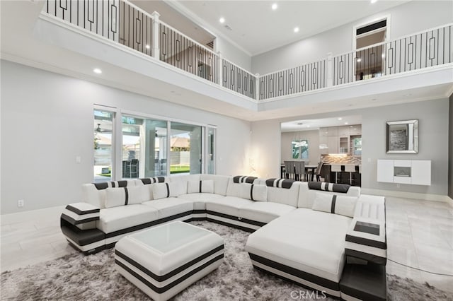 living room with a towering ceiling, tile patterned floors, and crown molding