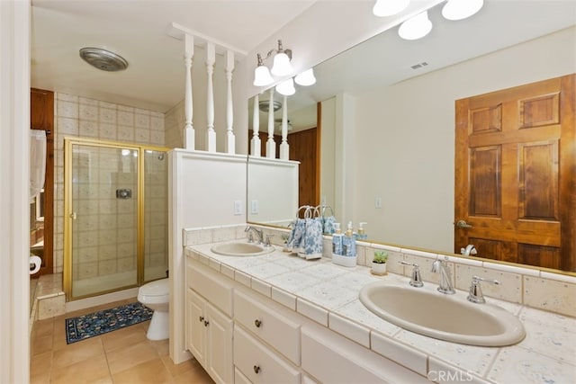 bathroom with tile patterned floors, vanity, toilet, and a shower with door