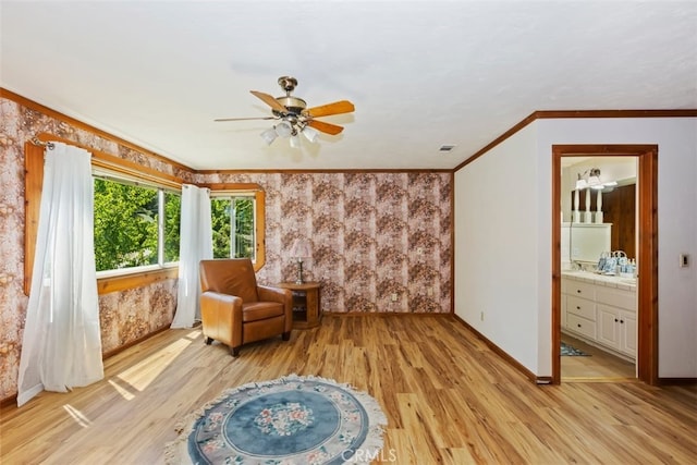 sitting room with ceiling fan, light wood-type flooring, and crown molding