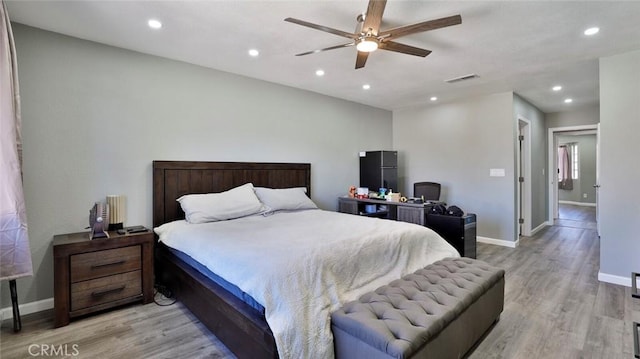 bedroom featuring black fridge, light wood-type flooring, and ceiling fan