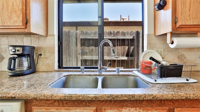 kitchen with light stone counters, sink, and tasteful backsplash