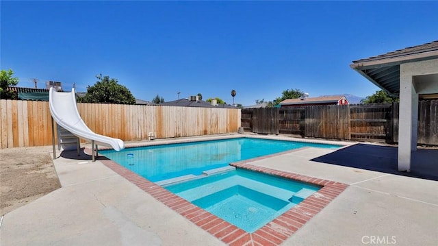 view of pool with an in ground hot tub, a water slide, and a patio area