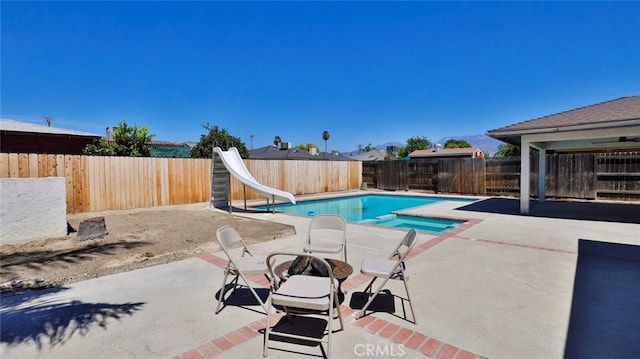 view of pool with an in ground hot tub, a water slide, and a patio