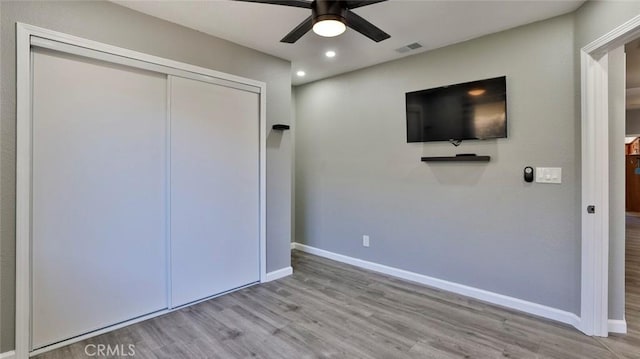 unfurnished bedroom featuring ceiling fan, light hardwood / wood-style floors, and a closet