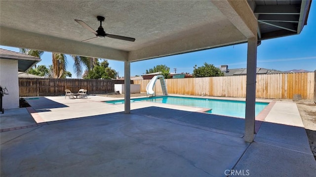 view of swimming pool with a patio, a water slide, and ceiling fan