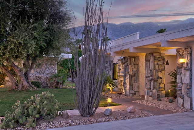 property exterior at dusk featuring a mountain view and a lawn