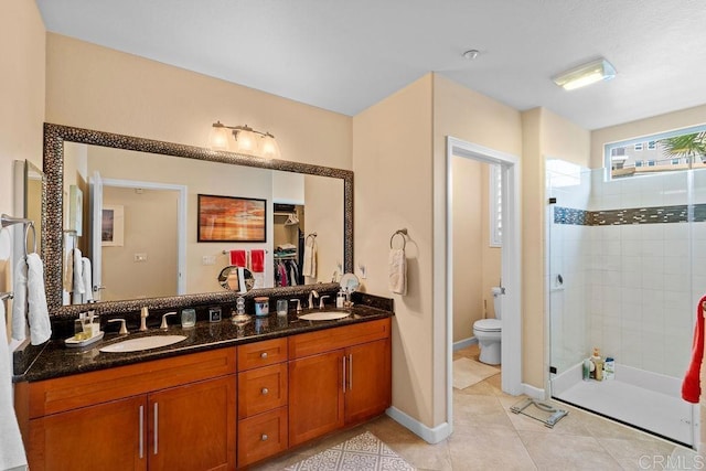 bathroom with tile patterned flooring, toilet, tiled shower, and a sink