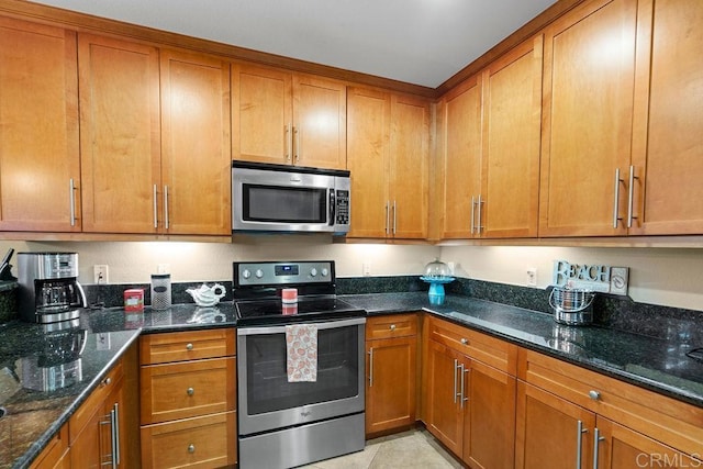 kitchen with dark stone counters, brown cabinetry, and appliances with stainless steel finishes