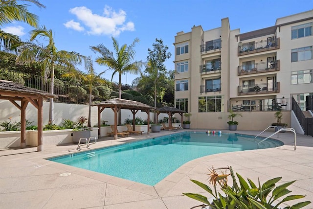 community pool with a gazebo, fence, and a patio