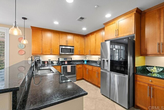 kitchen with visible vents, a peninsula, brown cabinetry, stainless steel appliances, and a sink