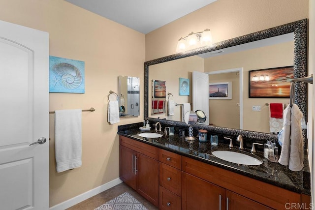 full bath featuring a sink, baseboards, double vanity, and tile patterned flooring