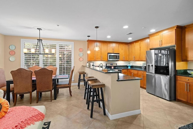 kitchen with a peninsula, stainless steel appliances, dark countertops, a kitchen breakfast bar, and a notable chandelier