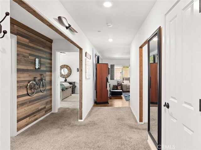 corridor featuring wood walls and light colored carpet