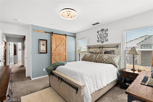 bedroom with a barn door and light colored carpet