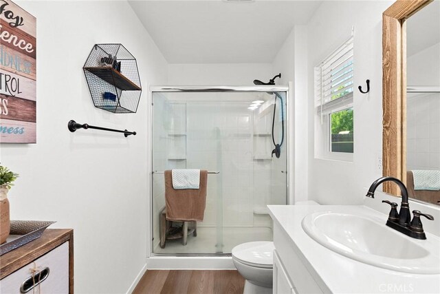 bathroom with vanity, a shower with shower door, hardwood / wood-style floors, and toilet