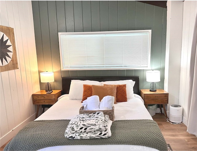 bedroom featuring wooden walls and hardwood / wood-style floors